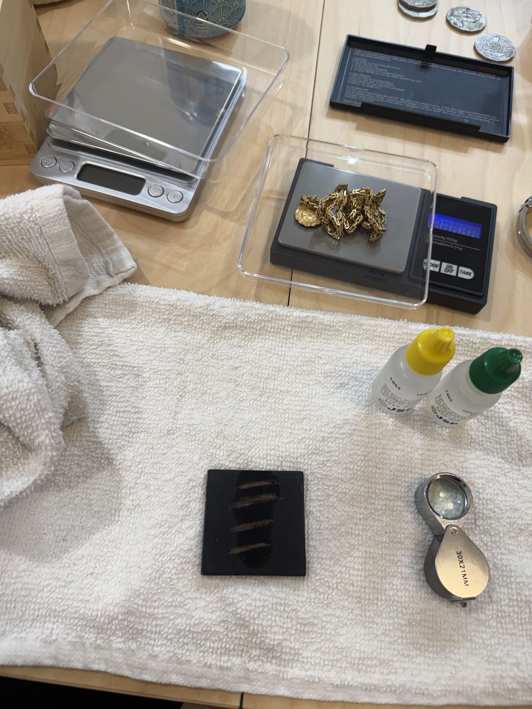 Gold testing acids, a touchstone, and a jeweler’s loupe used during evaluation